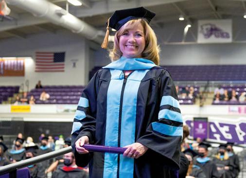 female doctor of education graduate smiles as she receives diploma