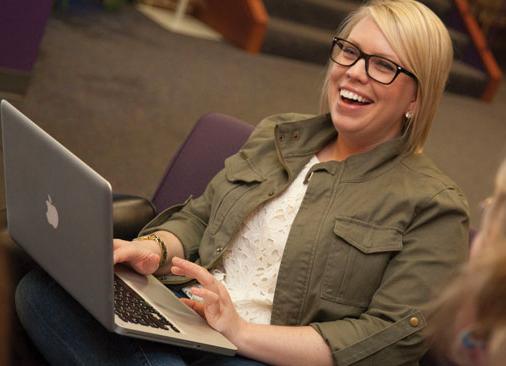 female student types on laptop and smiles